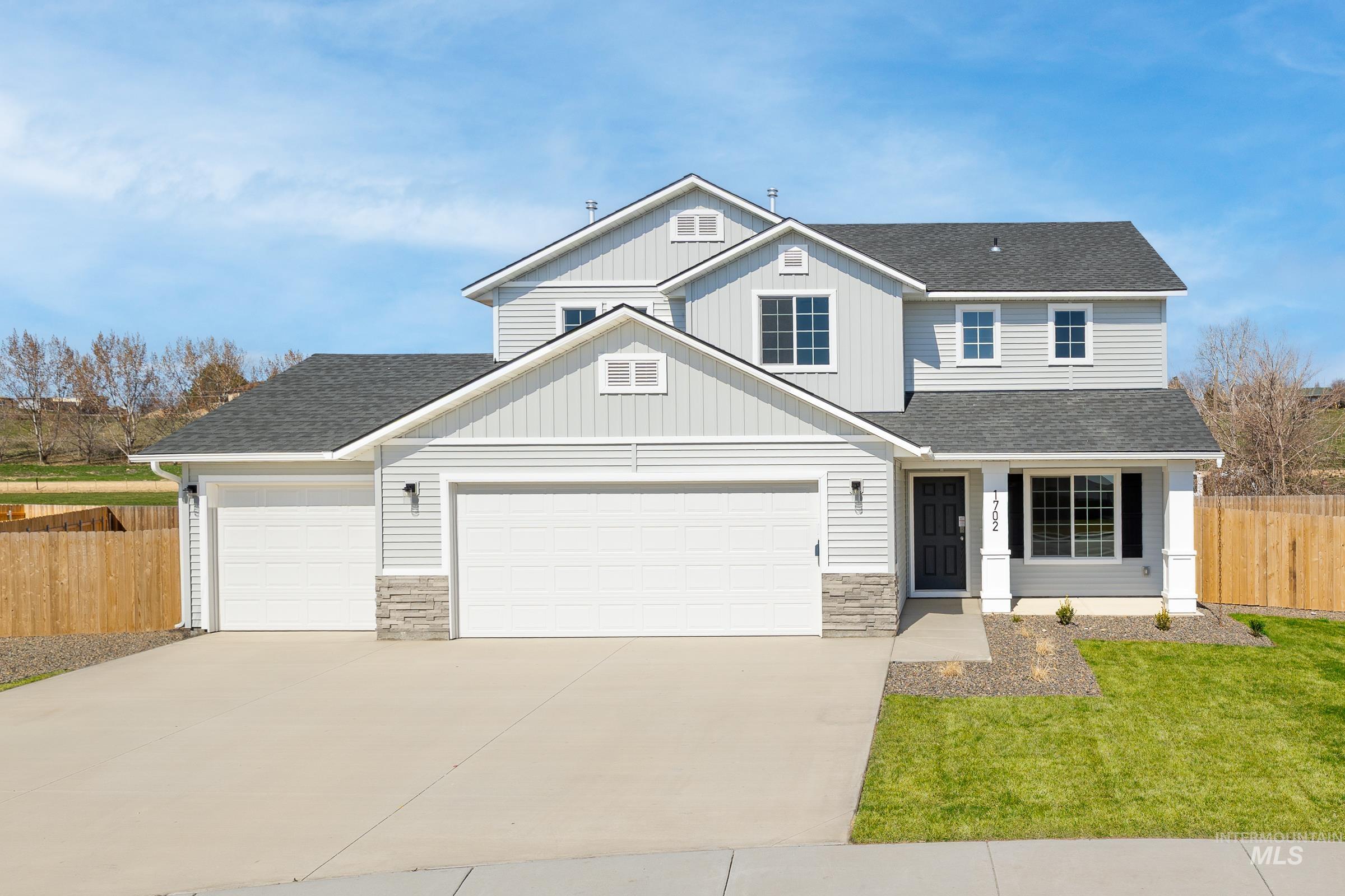 View of front of home with roof with shingles, a garage, driveway, and stone siding
