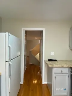 a view of a hallway with wooden floor and a livingroom with furniture