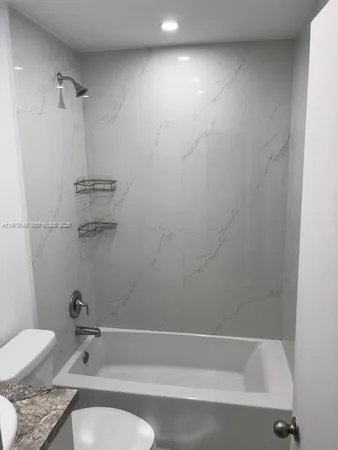 a bathroom with a granite countertop bathtub shower and toilet