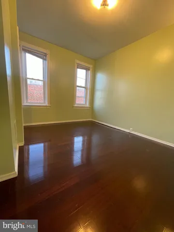 a view of empty room with window and wooden floor