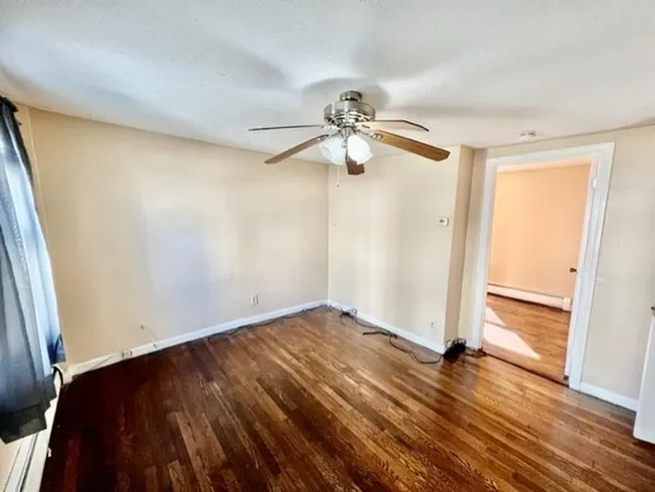 an empty room with wooden floor chandelier fan and closet area