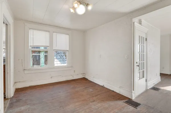 an empty room with windows and chandelier fan