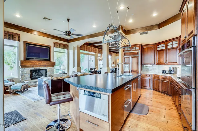 a kitchen with stainless steel appliances granite countertop a sink a stove and a wooden floors