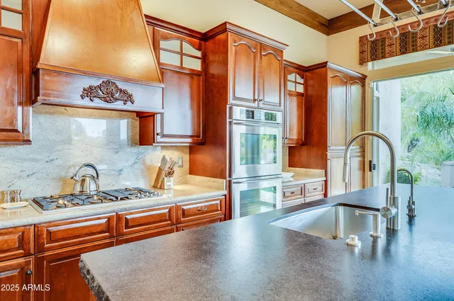 a kitchen with stainless steel appliances granite countertop a sink a stove and a wooden cabinets