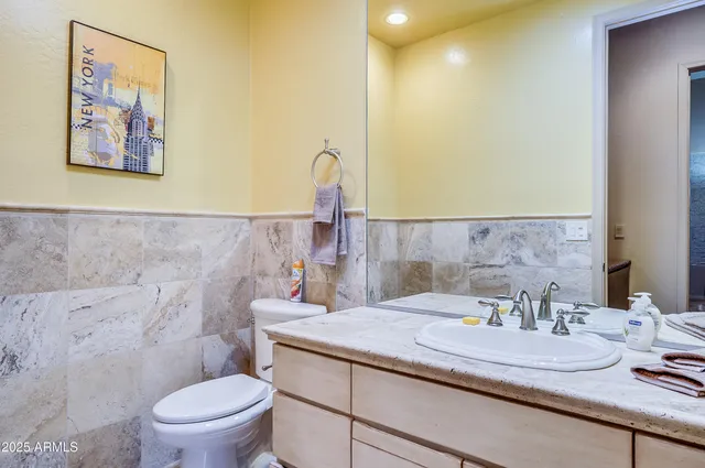 a bathroom with a granite countertop sink and a toilet