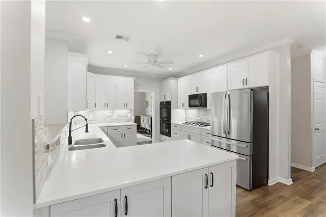 a large white kitchen with a sink and dishwasher with wooden floor