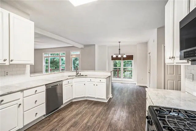 a large kitchen with wooden floors and white cabinets