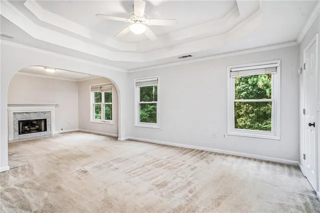 an empty room with windows fireplace and fan