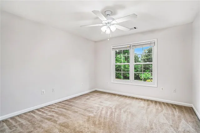 an empty room with a chandelier fan and windows