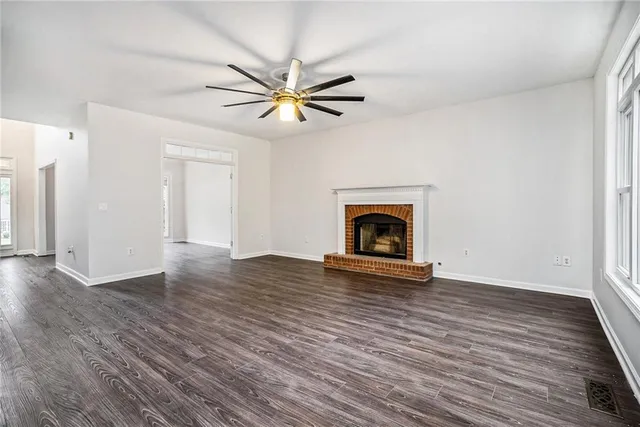 a view of an empty room with wooden floor and a fireplace