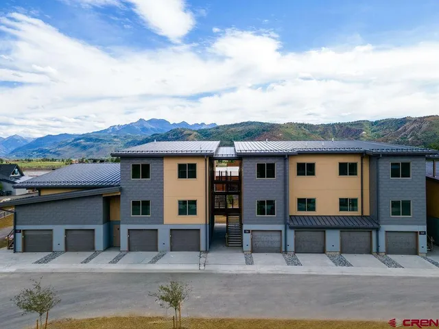 a view of a white house with large windows and a small yard