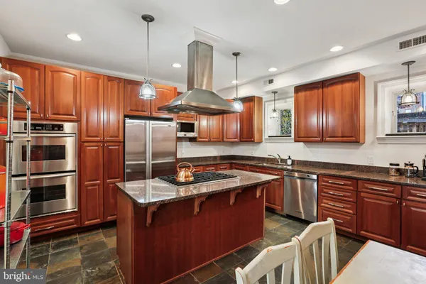 a kitchen with stainless steel appliances granite countertop a sink a stove a refrigerator cabinets and wooden floor