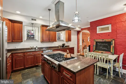 a kitchen with a stove a sink and chairs