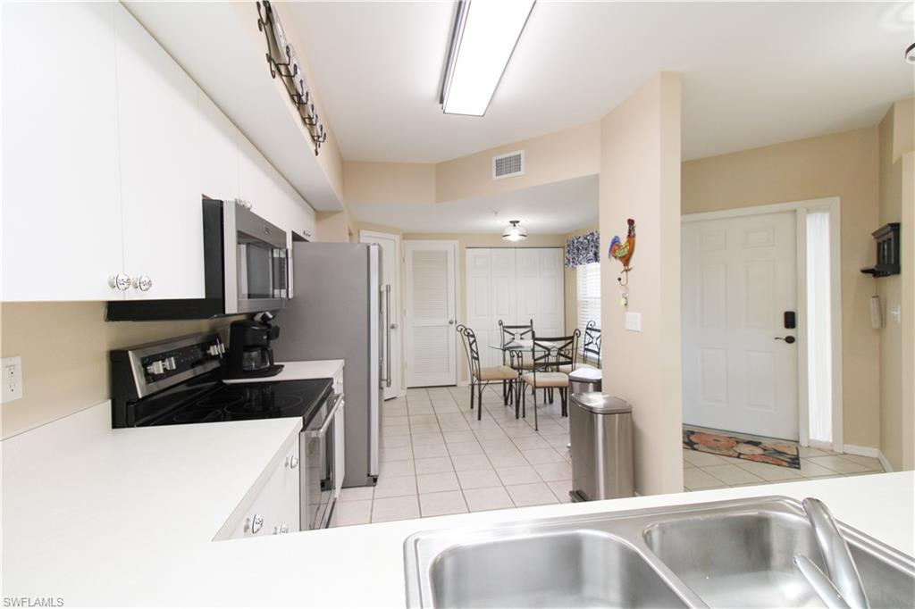 5025 Cedar Springs Drive, Unit 102 Naples, FL 34110 - Photo 23 of 50 Kitchen featuring light tile patterned flooring, sink, appliances with stainless steel finishes, and white cabinetry