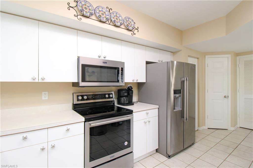 5025 Cedar Springs Drive, Unit 102 Naples, FL 34110 - Photo 25 of 50 Kitchen featuring white cabinetry, light tile patterned floors, and stainless steel appliances