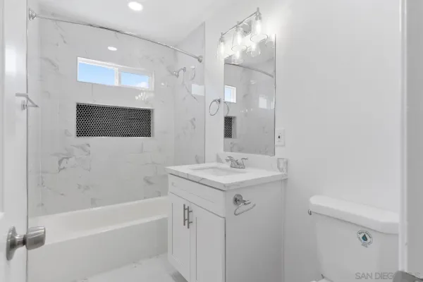 a bathroom with a sink a toilet a mirror and shower