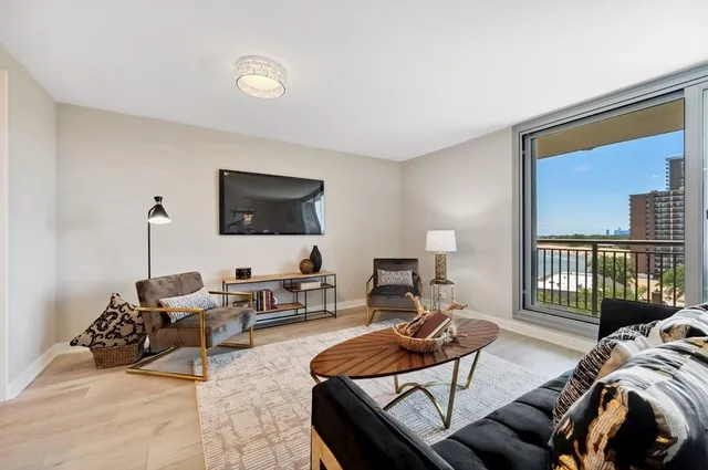 a living room with furniture a flat screen tv and a large window
