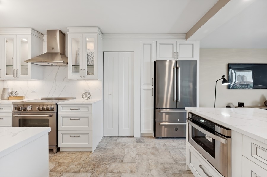 6007 North Sheridan Road, Unit 7J Chicago, IL 60660 - Photo 9 of 25 a kitchen with white cabinets and stainless steel appliances
