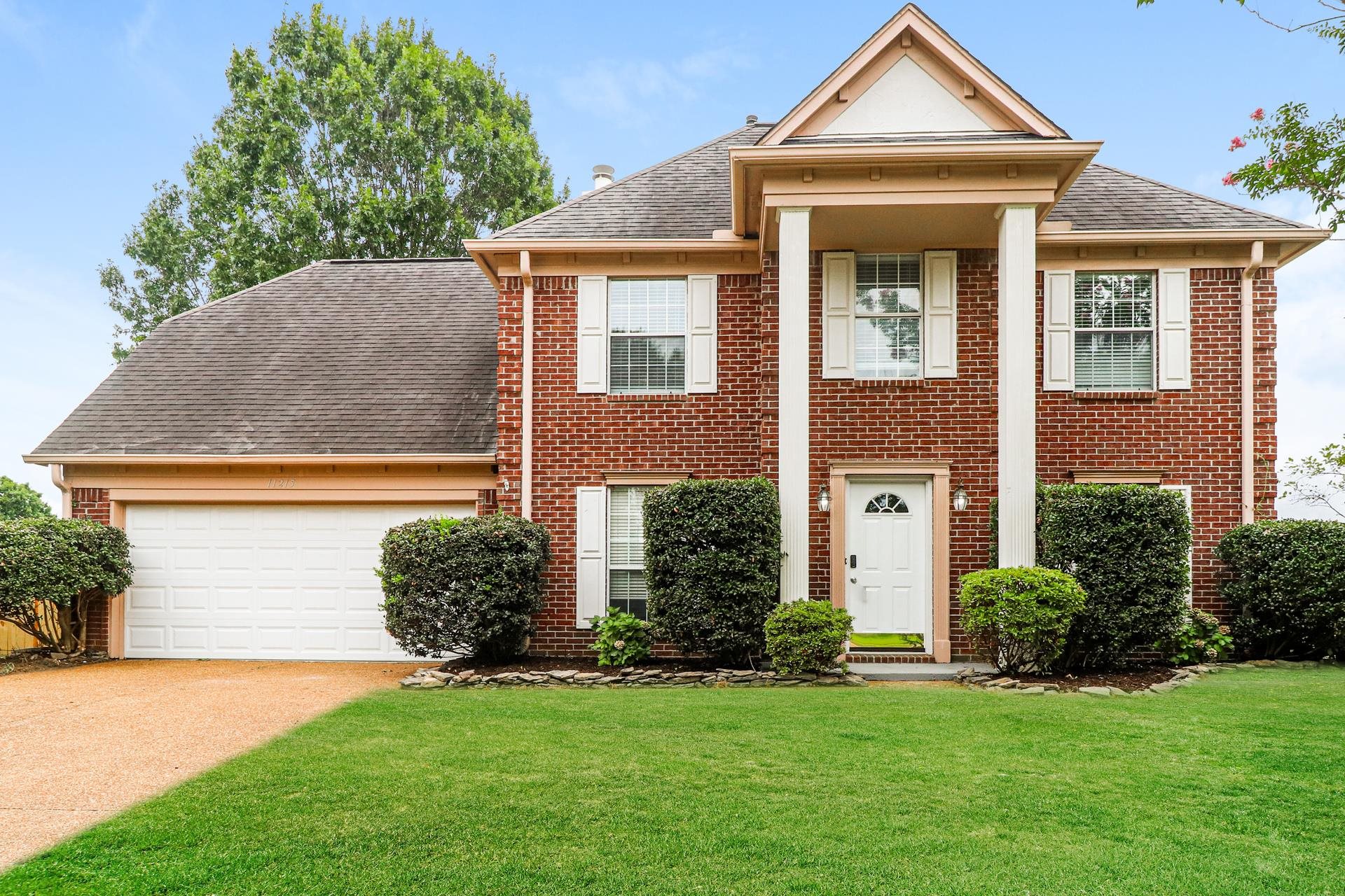 a front view of a house with a yard and trees