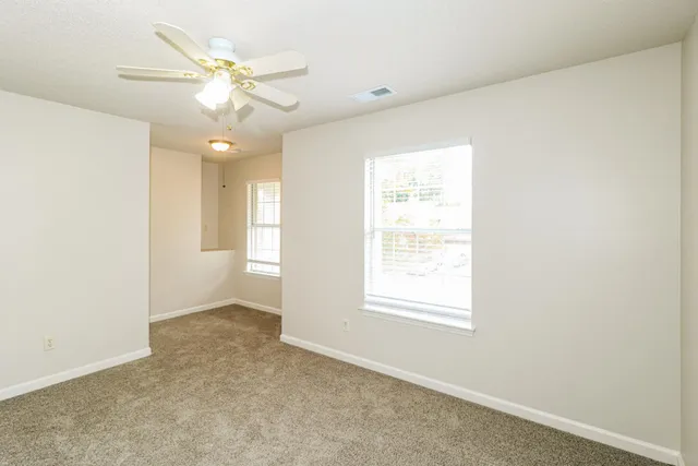 an empty room with windows and fan
