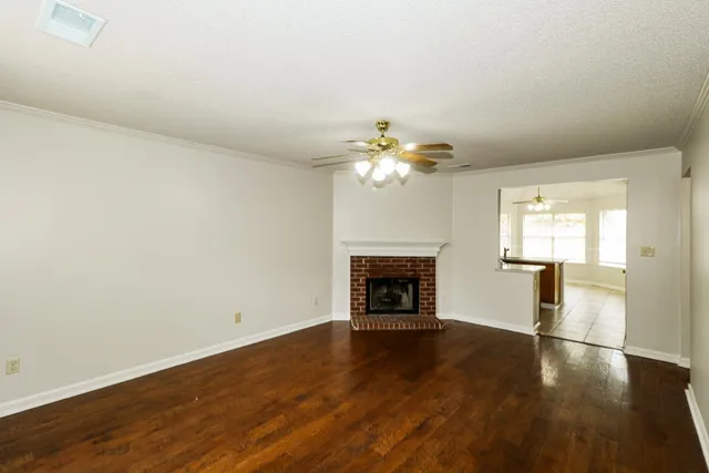 an empty room with wooden floor fireplace and windows