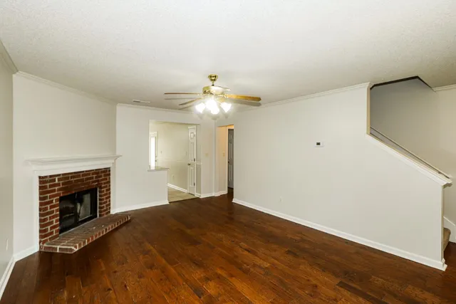 a view of an empty room with wooden floor fireplace and a window