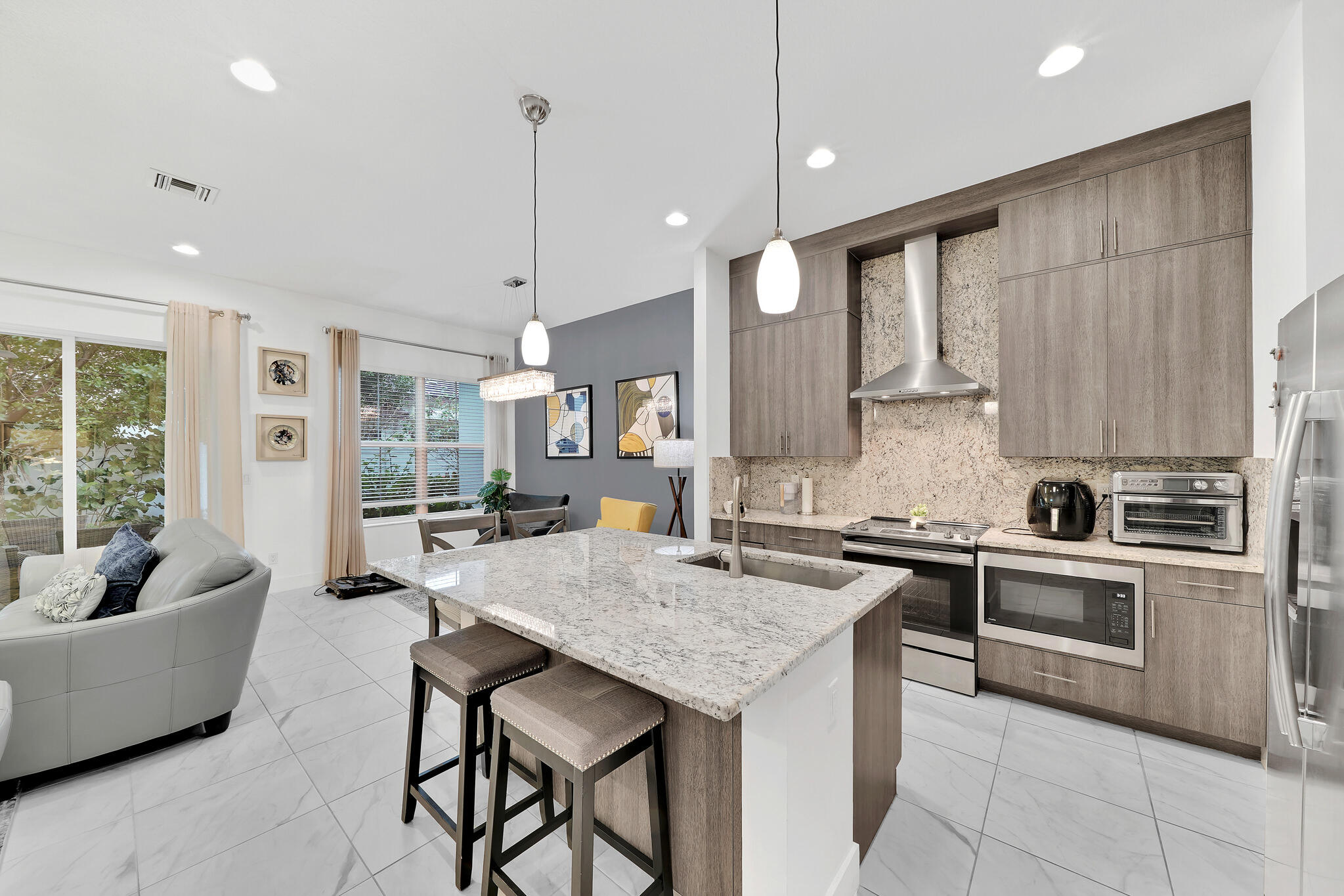 4821 Pointe Midtown Road Palm Beach Gardens, FL 33418 - Photo 8 of 62 a kitchen with granite countertop a stove a sink a kitchen island with chairs and cabinets