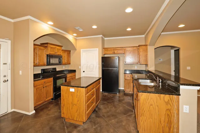 a kitchen with stainless steel appliances granite countertop a refrigerator a stove and a sink
