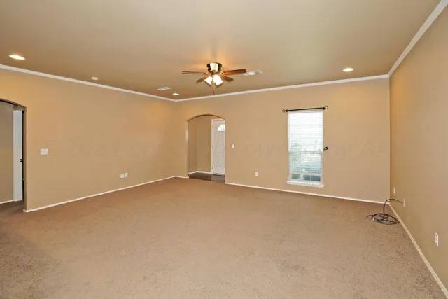an empty room with chandelier fan and windows