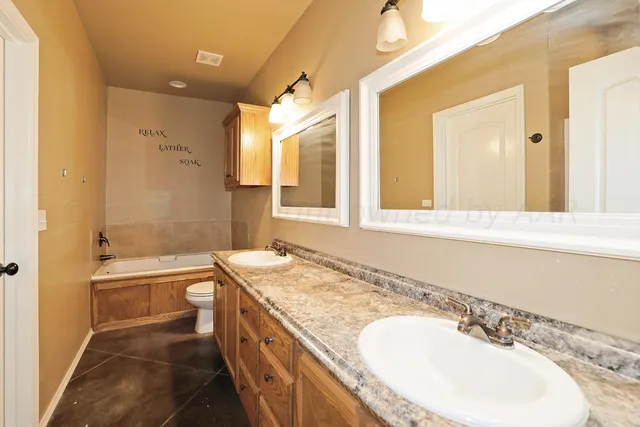 a bathroom with a granite countertop sink a toilet a mirror and bathtub