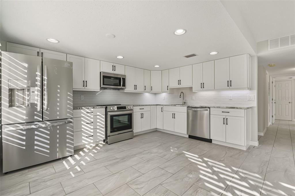 5055 North Beach Road, Unit 108 Englewood, FL 34223 - Photo 5 of 36 a kitchen with stainless steel appliances granite countertop a stove a sink and a refrigerator