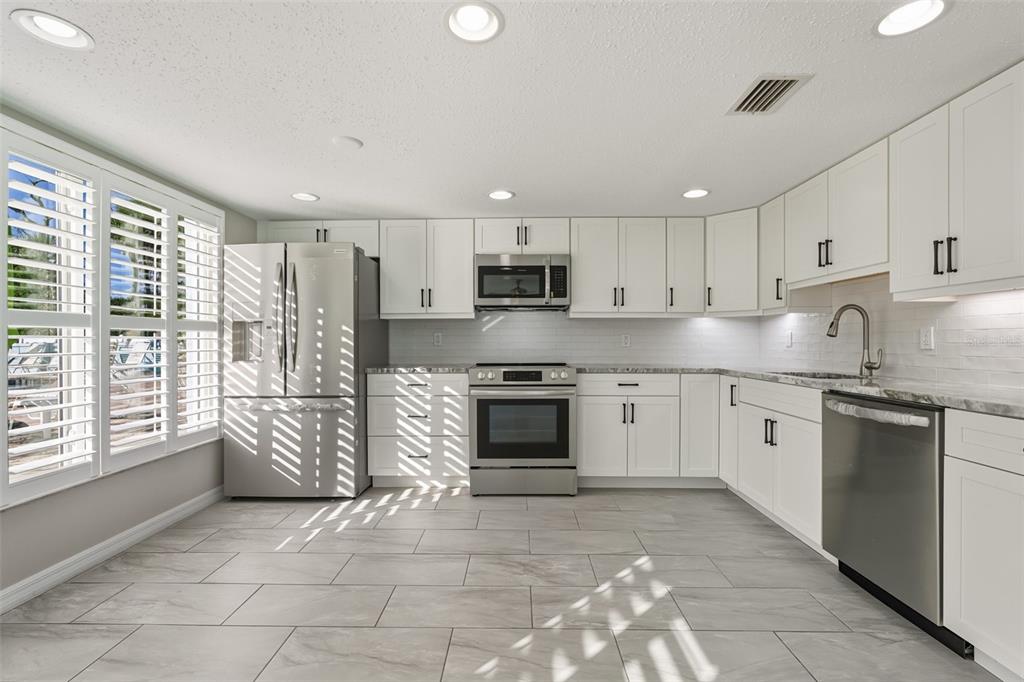 5055 North Beach Road, Unit 108 Englewood, FL 34223 - Photo 6 of 36 a kitchen with stainless steel appliances granite countertop a stove top oven a sink a refrigerator and white cabinets
