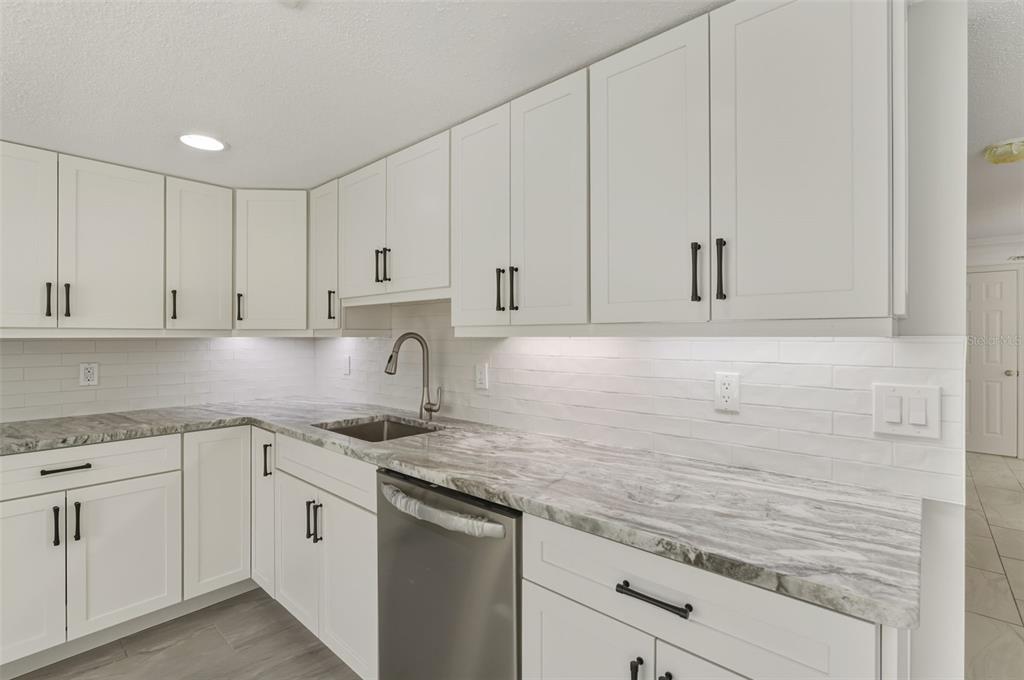 5055 North Beach Road, Unit 108 Englewood, FL 34223 - Photo 8 of 36 a kitchen with granite countertop white cabinets and white stainless steel appliances
