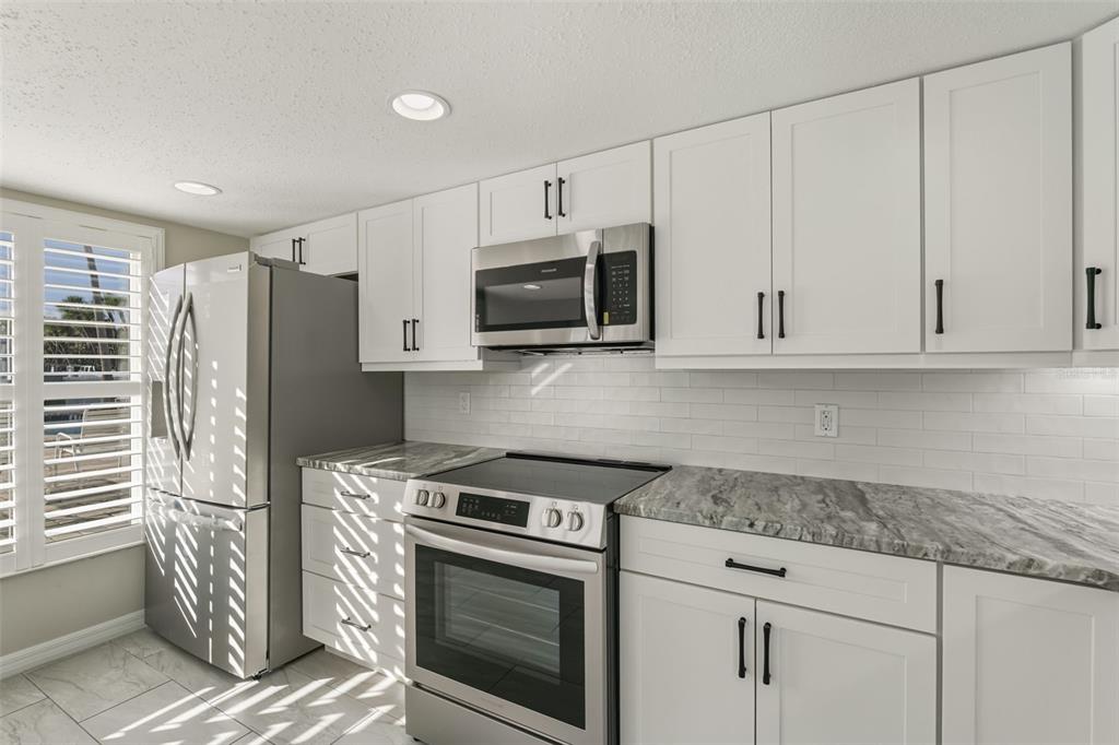 5055 North Beach Road, Unit 108 Englewood, FL 34223 - Photo 9 of 36 a kitchen with stainless steel appliances white cabinets and a stove top oven