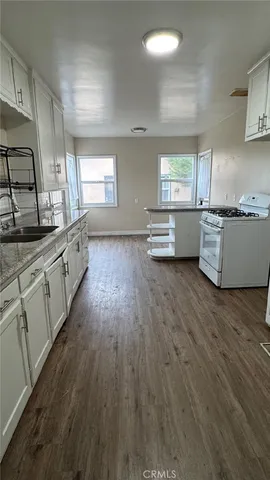 a kitchen with stainless steel appliances wooden floors and white cabinets