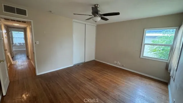a view of empty room with wooden floor and fan