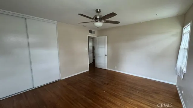 an empty room with wooden floor a ceiling fan and windows