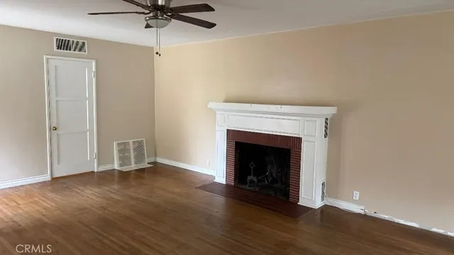 an empty room with wooden floor a fireplace a ceiling fan and closet