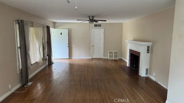 an empty room with wooden floor and a fireplace