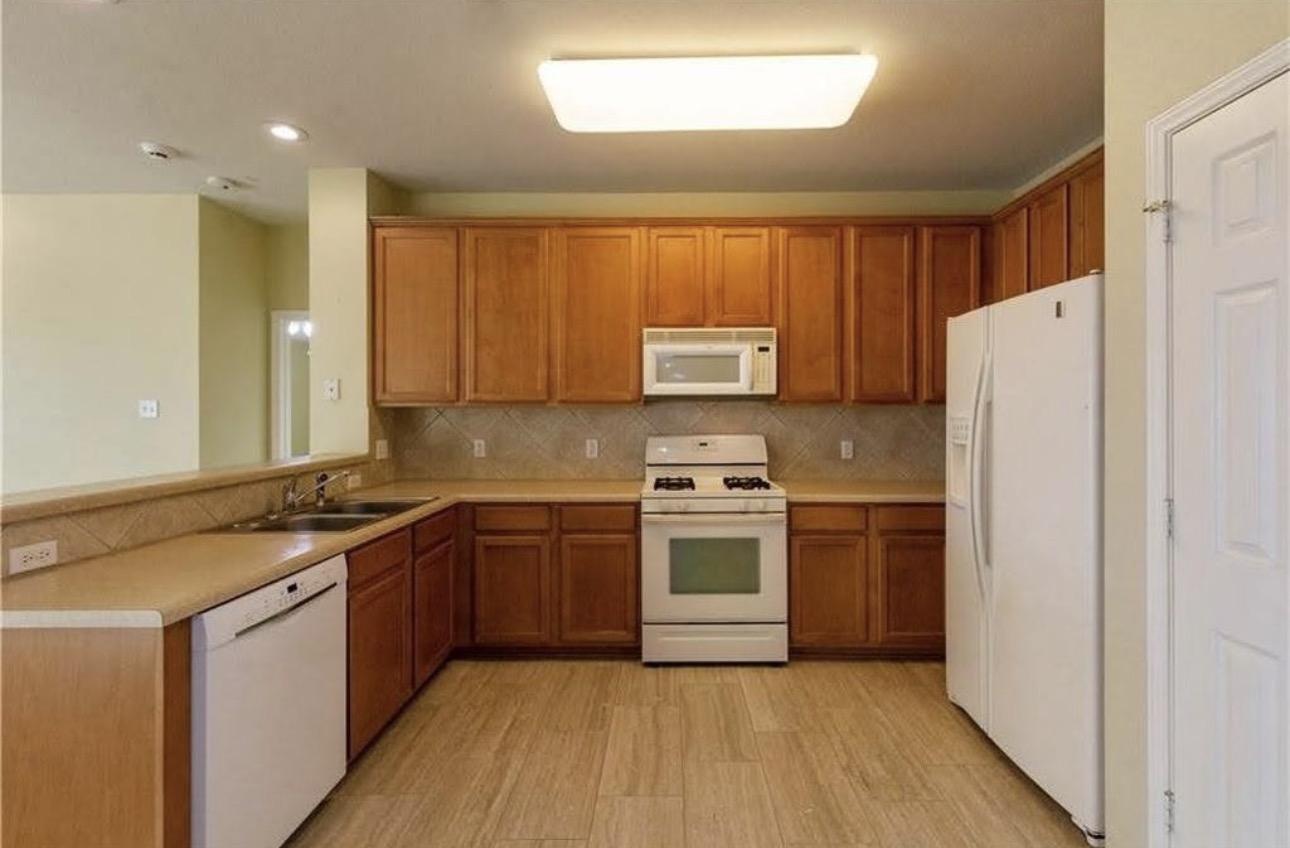 1900 Scofield Ridge Parkway, Unit 3101 Austin, TX 78727 - Photo 8 of 24 Kitchen featuring wood-finish flooring, a full suite of white appliances, warm-toned cabinetry, light countertops, and a tiled backsplash