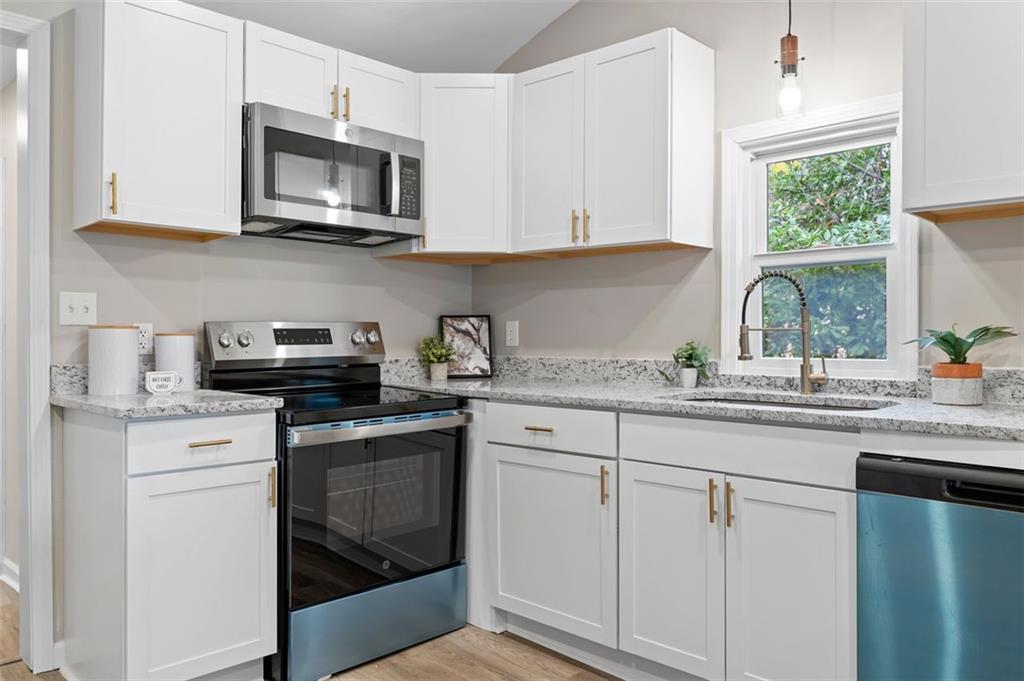 118 Perry Street Monroe, GA 30655 - Photo 12 of 30 a kitchen with granite countertop white cabinets and white appliances
