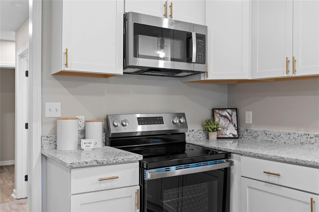 118 Perry Street Monroe, GA 30655 - Photo 13 of 30 a kitchen with stainless steel appliances granite countertop a stove a microwave and cabinets