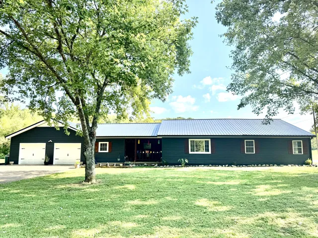 a view of a house with a yard and a large tree