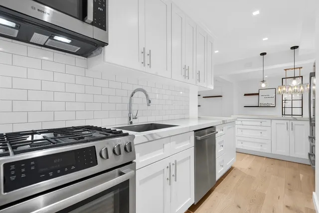 a kitchen with stainless steel appliances granite countertop a stove and white cabinets