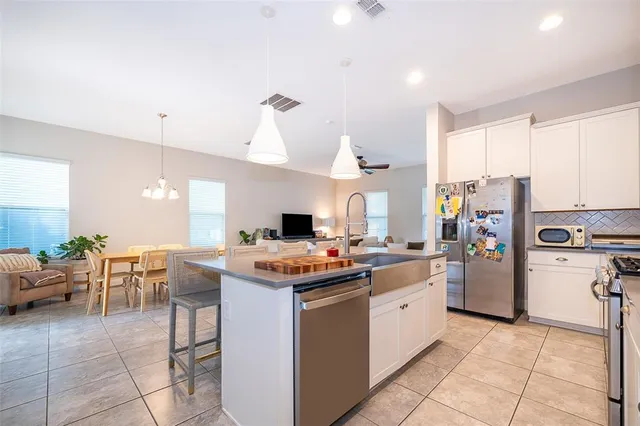 a kitchen with a stove a refrigerator and chairs
