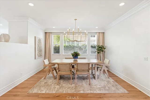 a dining room with wooden floor a chandelier a wooden table and chairs