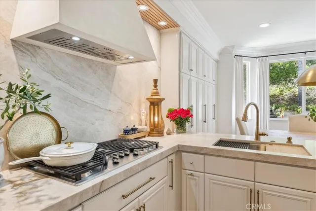 a kitchen with a stove a sink cabinets and a window