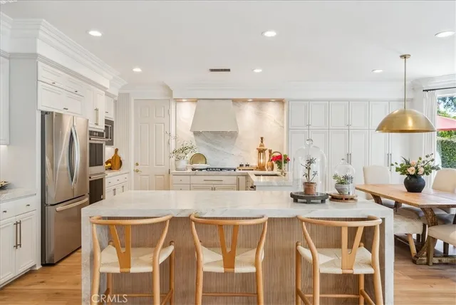 a kitchen with stainless steel appliances granite countertop a table chairs sink and refrigerator