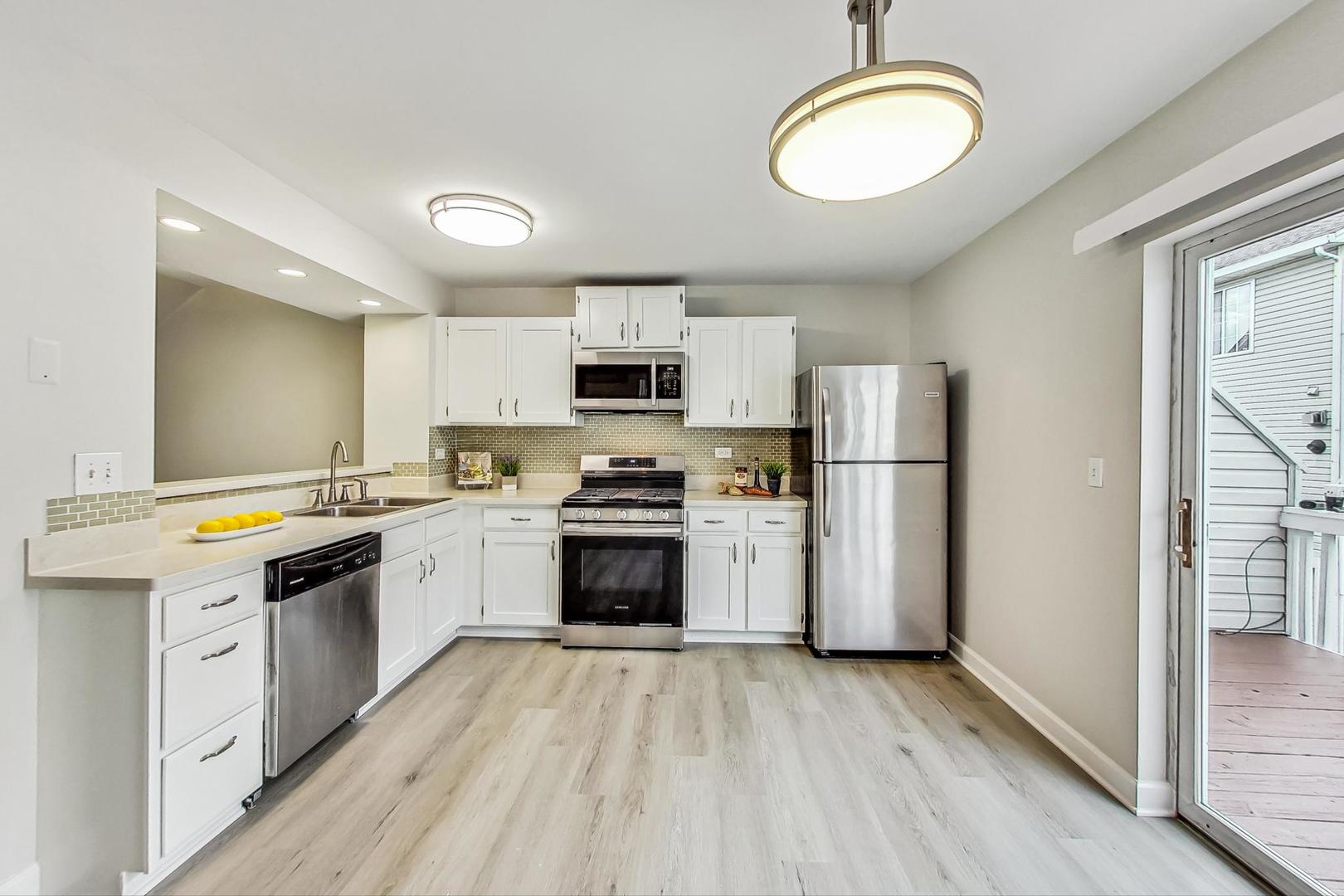 313 Rosebud Court, Unit 313 Bolingbrook, IL 60440 - Photo 8 of 31 a kitchen with a white cabinets and wooden floor