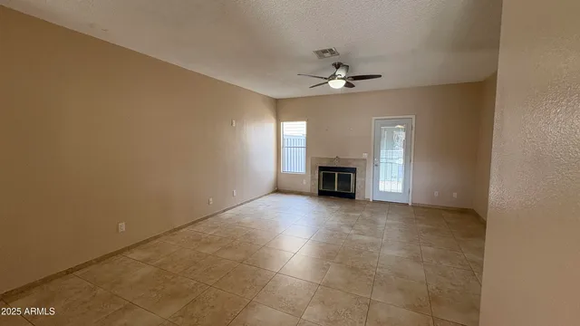 an empty room with a ceiling fan and a fireplace